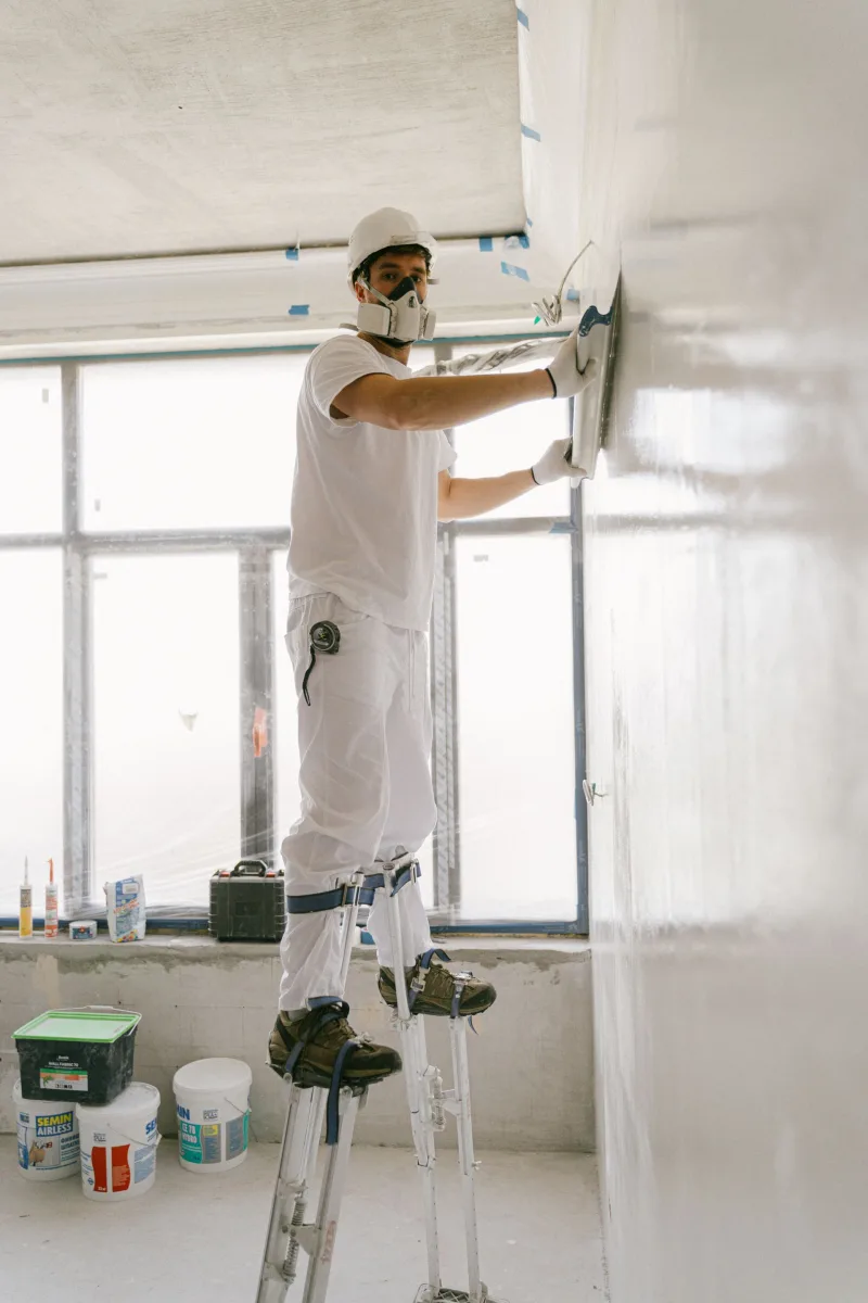 Finisher on drywall stilts applying a Level 5 skim coat